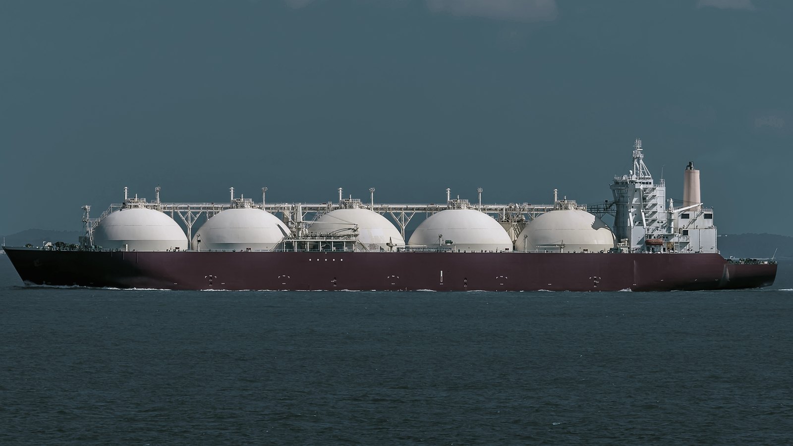 An LNG carrier under way in open water, seen from the beam