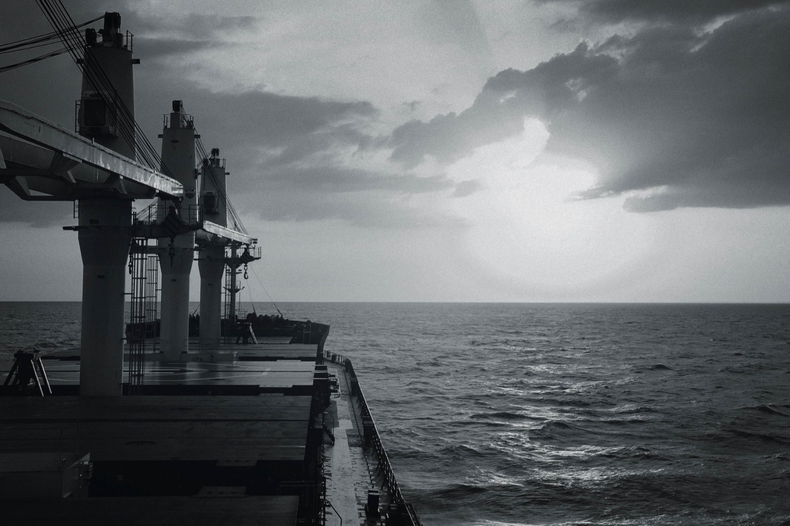 A bulk carrier's deck and cranes at dusk on the open sea